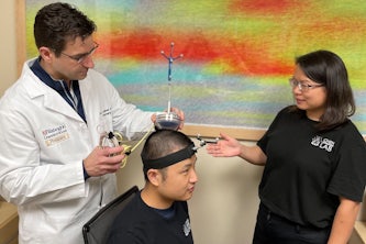 Graduate student Lu Xu (center) wears a device co-invented by Washington University’s Eric C. Leuthardt, MD, (left) a professor of neurosurgery at the School of Medicine, and by Hong Chen, PhD, (right) an associate professor of biomedical engineering at the university's McKelvey School of Engineering. The technology was developed so that noninvasive biopsies could be performed in adults with brain tumors. It has been granted U.S. Food and Drug Administration "Breakthrough Device" designation, which helps accelerate the process toward market approval.
