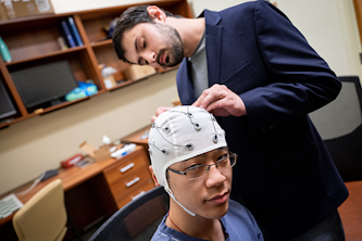 Postdoctoral research fellow Matthew Singh adjusts electrodes for graduate student Ruiqi Chen. ​​​​​​(Photo: Sean Garcia)