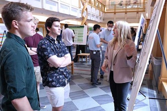 Melanie Roberts, an undergraduate researcher with the Center for Engineering MechanoBiology, presents her poster to other STEM Poster Palooza attendees.
