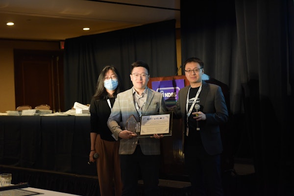 Hongchao Zhang, center, accepts the 2023 General Motors AutoDriving Security Award on behalf of Andrew Clark's research team. 