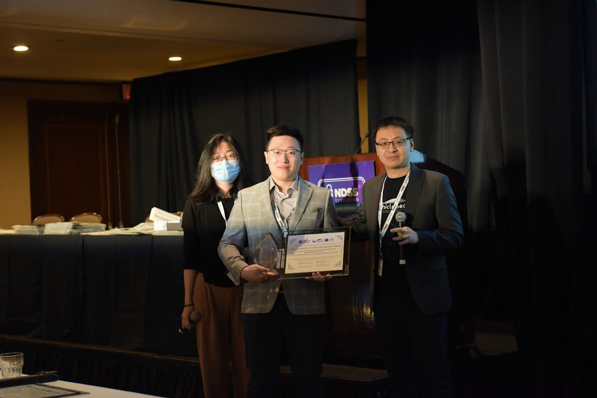 Hongchao Zhang, center, accepts the 2023 General Motors AutoDriving Security Award on behalf of Andrew Clark's research team.